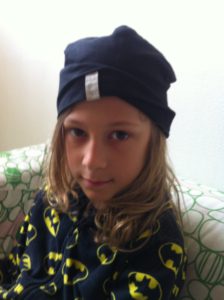 Marvin sitter i en soffa. Han har långt hår, en blå mössa och en tröja med batman-märken.