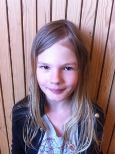 Matilda står framför en vägg. Hon har långt blont hår och en svart jacka.