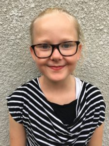 Nelly står mot en grå bakgrund och ler. 