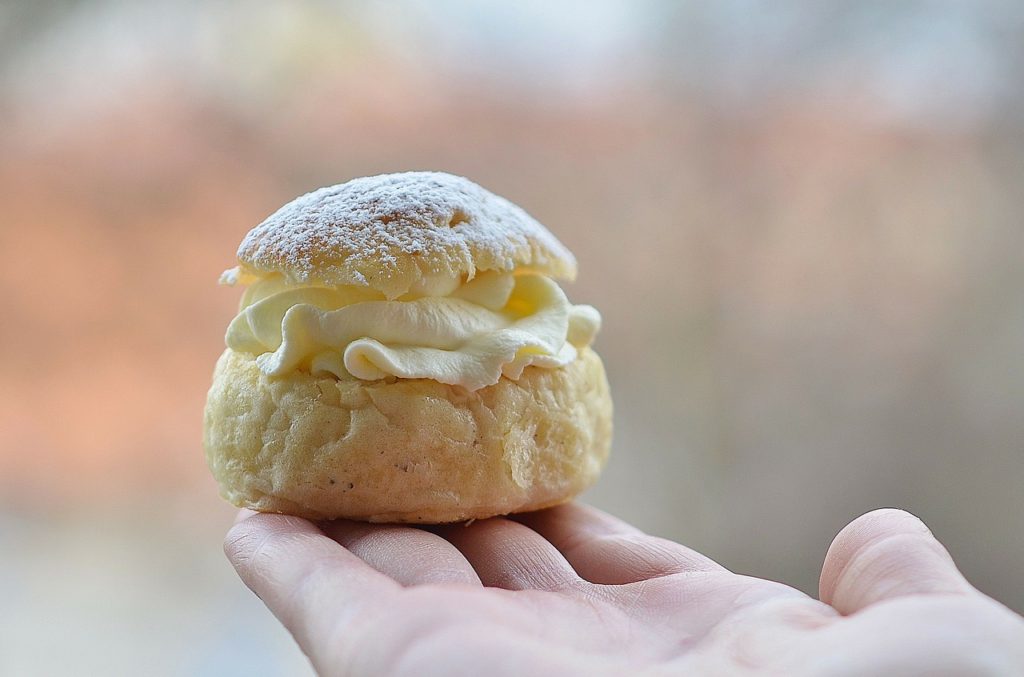 En hand som håller en vanlig semla. 