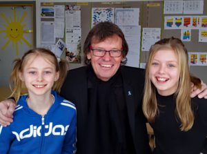 Närbild på en vuxen och två barn som tittar in i kameran Alla ler.