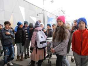 Barn står och väntar utanför en stor byggnad.