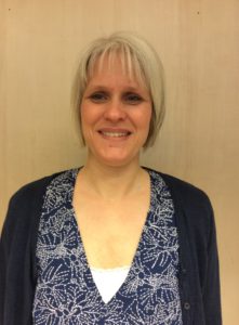 Bild på person med mönstrad blus och blå kofta över.