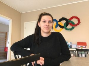 En person med svart tröja och svart långt hår sitter vid ett bord.