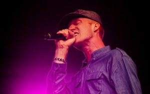 Artisten står på scen och sjunger i en mick.