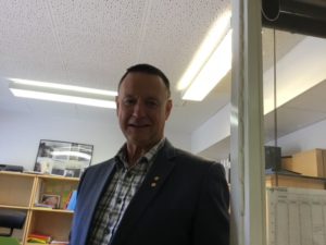 En person med kavaj och skjorta står på ett kontor.