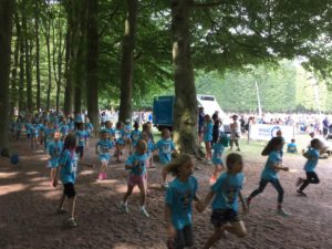 Barn med blåa tröjor springer på grusgången.