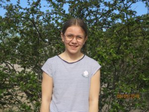 Julia står framför en buske.