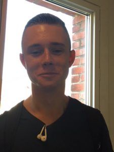 Benjamin står framför ett fönster. Han har bakåtslickat hår med mycket gelé i och ett par hörlurar hängande ur tröjan.