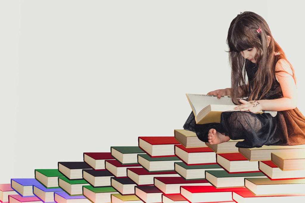 Ett barn sitter på en hög med böcker och läser.