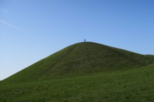 Grön kulle med pojke uppe på toppen