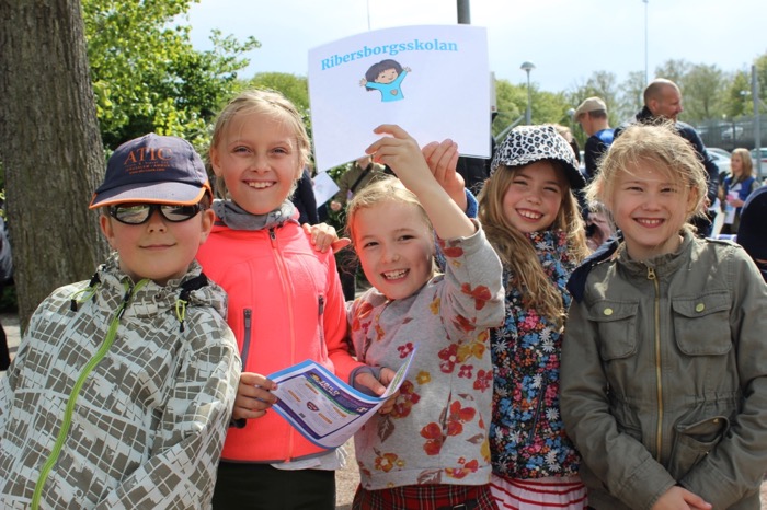 Fem glada elever utanför en fotbollsarena