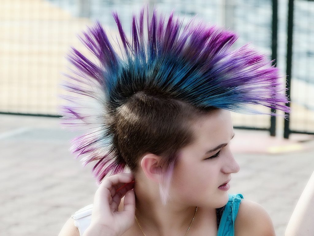 Bild på ej tjej i punkfrisyr. Hon har tuppkam i flera olika färger och rakat hår på sidorna av huvudet.