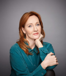 Rowling håller huvudet i handen. Hon ser ut att vara ungefär 45 år gammal. Hon tittar ganska fundersamt och allvarligt in i kameran. 