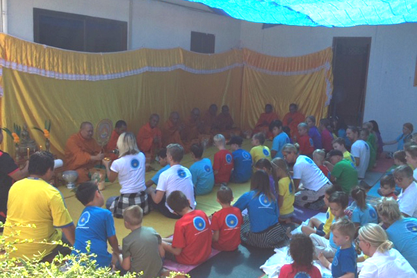 Munkar som sitter i en lång rad framför skolans elever.