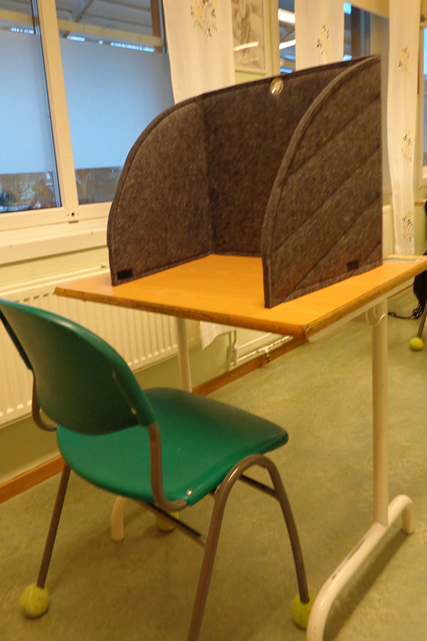 En skolbänk med en skärm på. Skärmen, skärmar av så att eleverna inte störs av saker runtomkring.