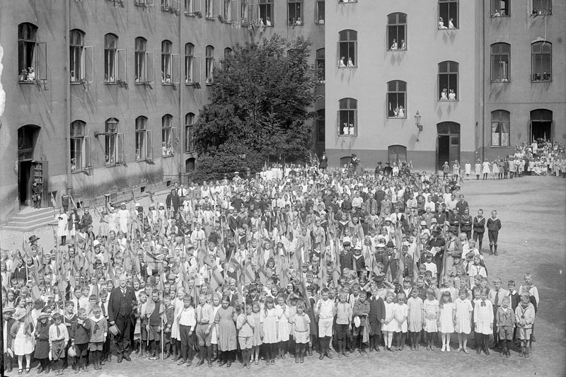 Elever som snart ska få sommarlov. De har samlats på gården utanför sin skola.